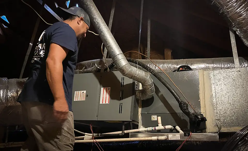 A NATE certified technician from American Heritage Air evaluates a customer's attic HVAC system.