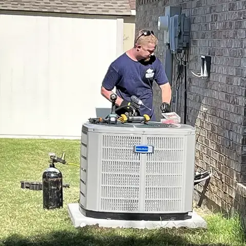 An American Heritage Air technician works on an American Standard air conditioner for a customer.