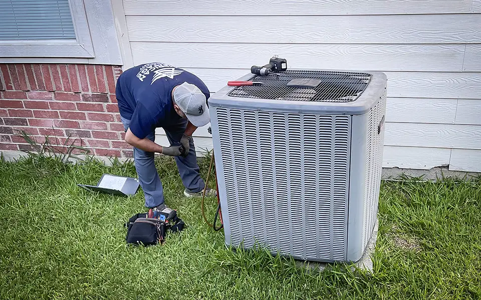 A technician works diligently on a customer's air conditioner.